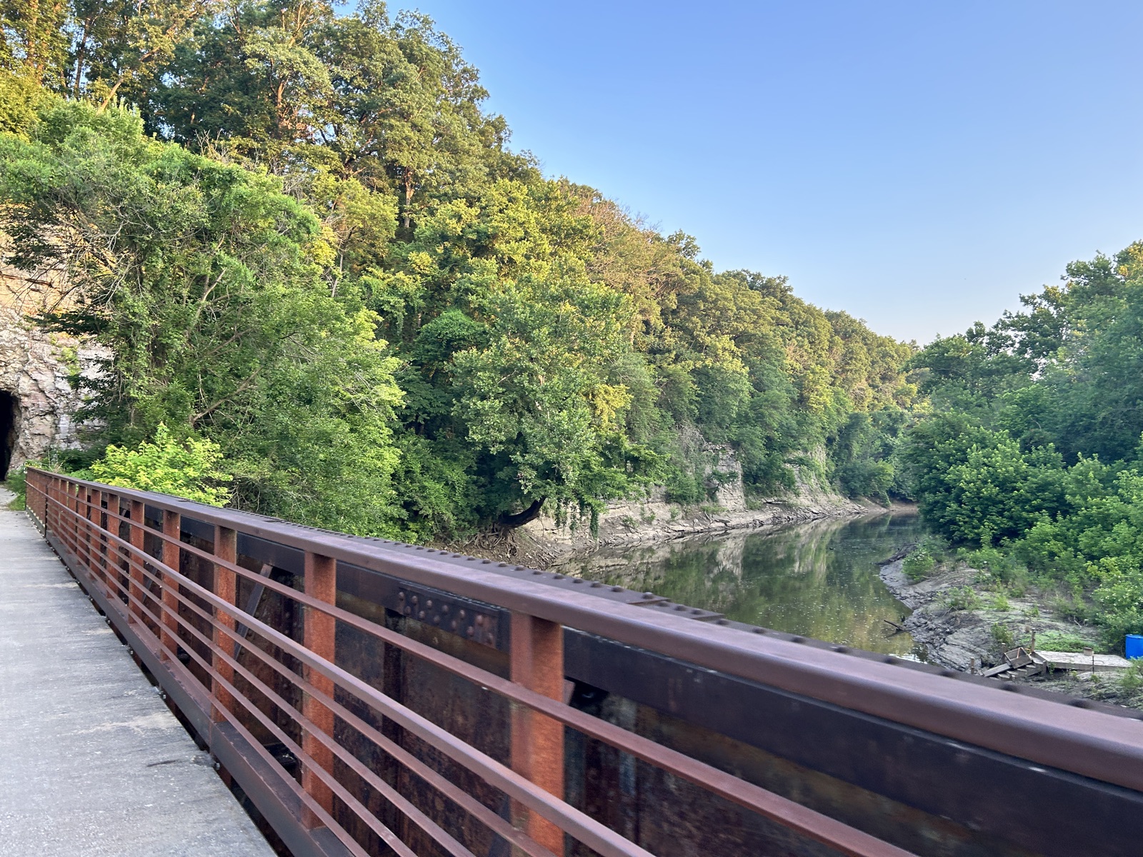 Rusted riveted girder of the Moniteau Creek bridge with limestone bluff beyond
